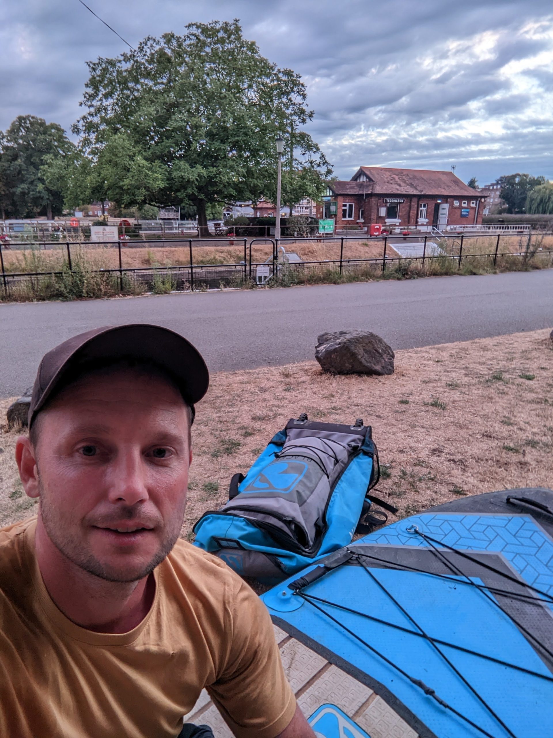 Tom sitting on the paddle board at Teddington Lock after paddle boarding the thames